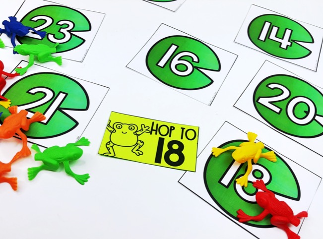 Number recognition activities: gross motor game. Lily pad cards with numbers and frog toys on number 18